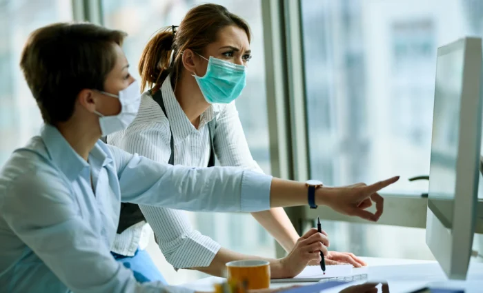 young-businesswoman-her-colleague-wearing-face-masks-while-working-computer-office-virus-epidemic