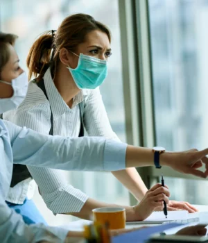young-businesswoman-her-colleague-wearing-face-masks-while-working-computer-office-virus-epidemic