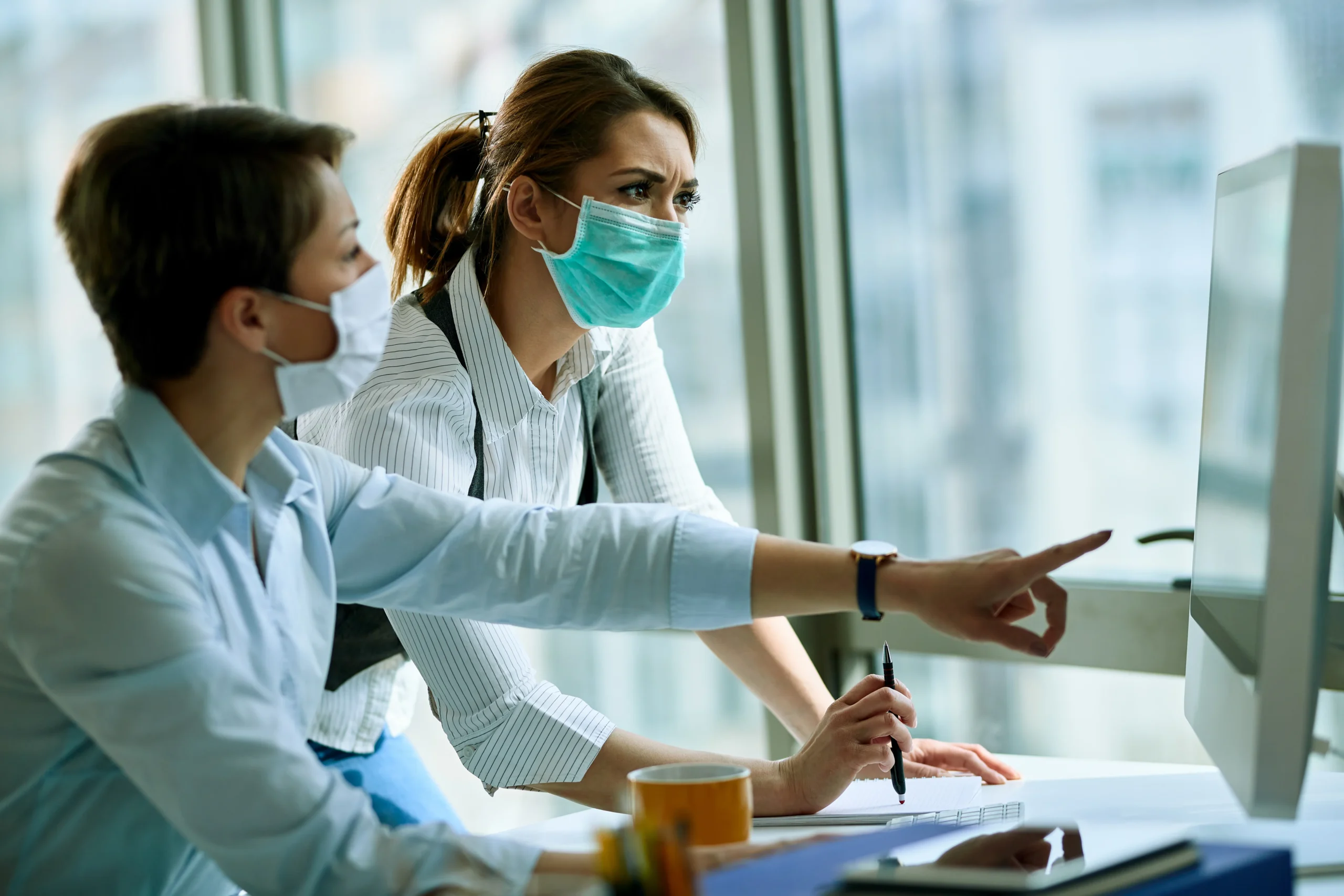 young-businesswoman-her-colleague-wearing-face-masks-while-working-computer-office-virus-epidemic